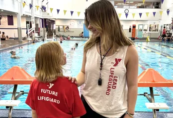 A lead lifeguard talking to a future lifeguard at the pool