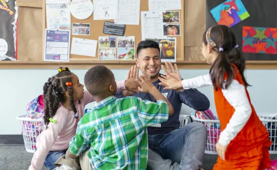 man high fiving young children in a child care setting