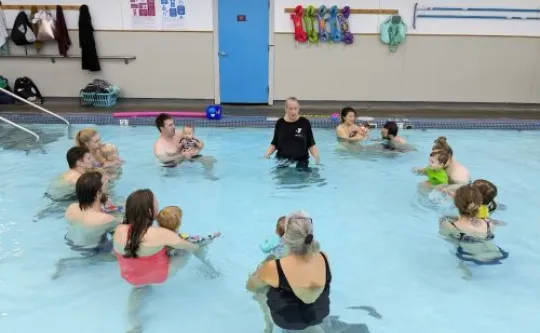Group of parents in shallow pool with instructor and infants