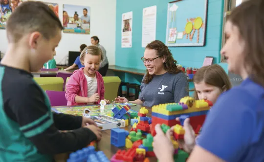 Woman playing legos with children in classroom setting