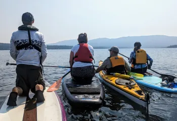 Group of people on a variety of paddle boards or kayaks together in the open water