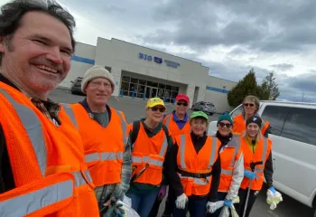 Group of YMCA staff and volunteers in orange vests as they finish up collecting garbage for Adopt-A-Hwy