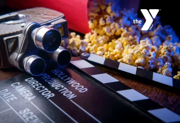 A photo of a movie clacker, old fashioned film camera and popcorn depicting a movie event advertisement