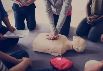 A group of people around a cpr dummy learning CPR and first aid