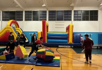 Fun times in a gymnasium with families and bouncy house.
