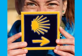 A woman holding a tile of a sun with an arrow.