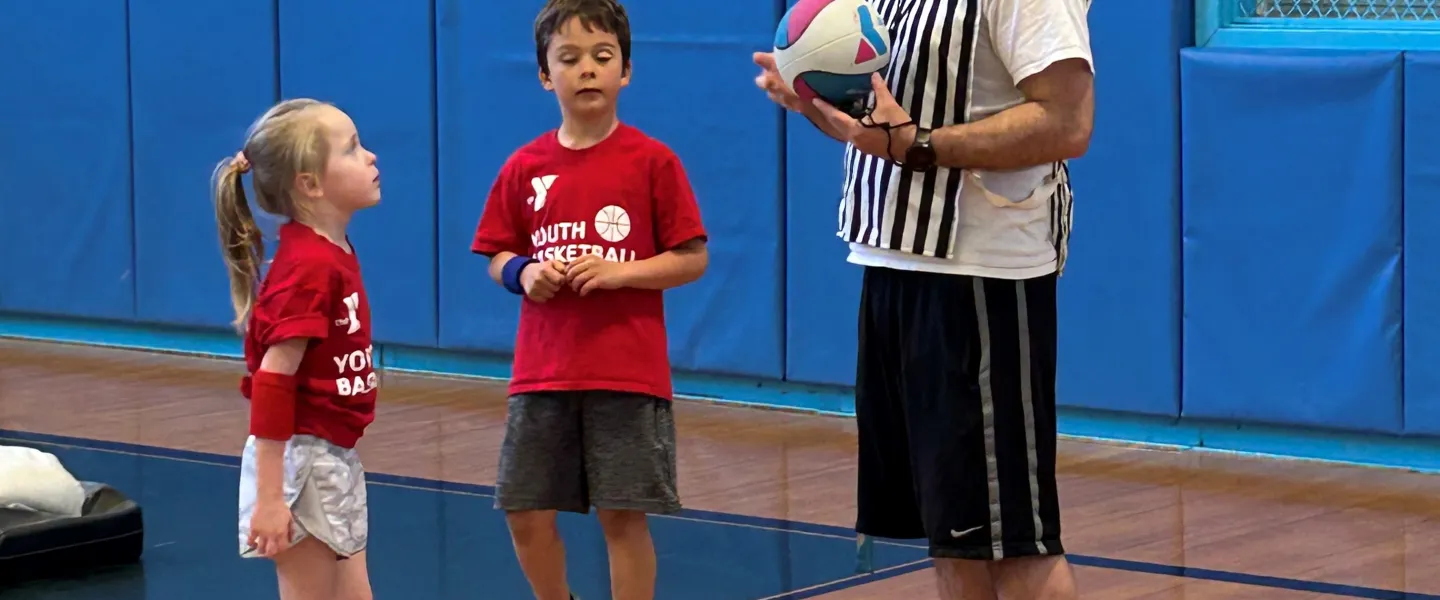 Youth playing basketball and talking to a referee