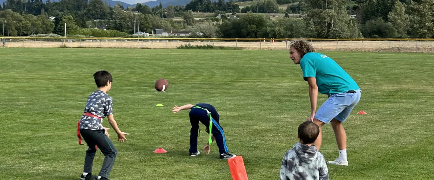 Youth practicing flag football with a YMCA coach