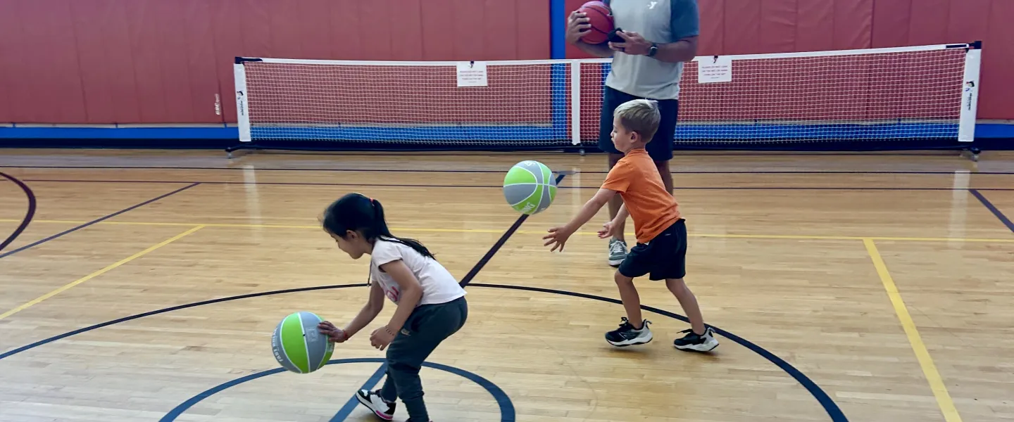 Toddlers learning how to dribble a basketball with their coach