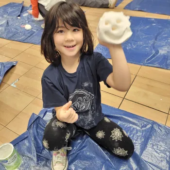 Child holding up a fake snowball made out of fake snow