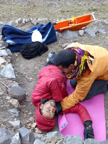 People in the wilderness crouched over someone who needs help; demonstrating first aid