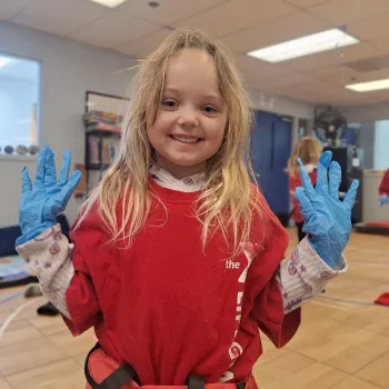 Girl at YMCA day camp with rubber gloves on from doing a craft