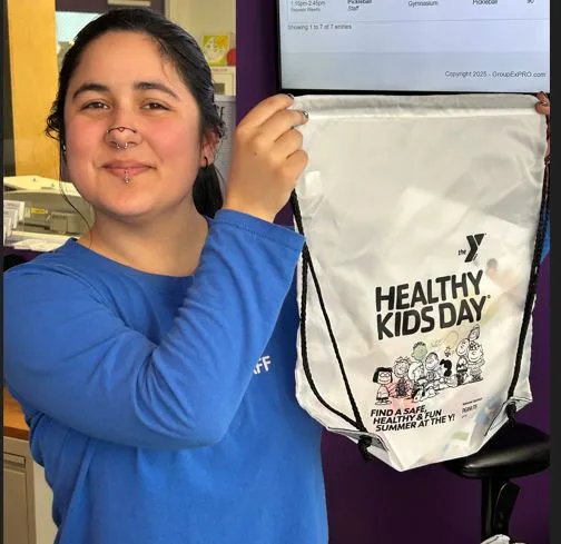 A woman holding a white Healthy Kids Day backpack