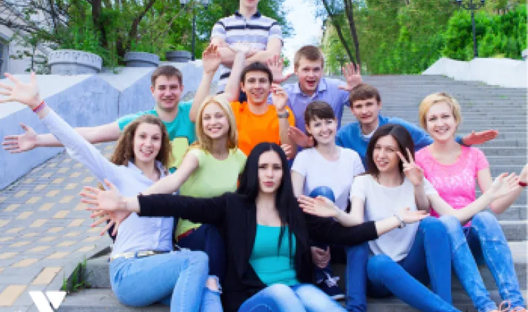 A group of mixed gender and mixed culture middle school youth sitting on school steps