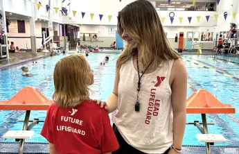 A lead lifeguard talking to a future lifeguard at the pool