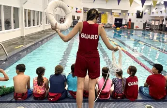 A lifeguard demonstrating skills to children at the pool.