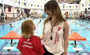 A lead lifeguard talking to a future lifeguard at the pool