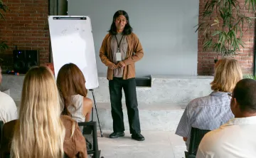 Graphic image of a person giving a wellness presentation to a mixed group of people.