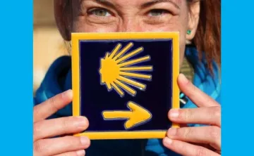 A woman holding a tile of a sun with an arrow.
